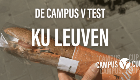 Op straat houdt iemand een verpakt broodje vast. Boven de afbeelding staat de tekst: DE CAMPUS V TEST KU LEUVEN, met CAMPUS CUP-logo’s in de hoeken.