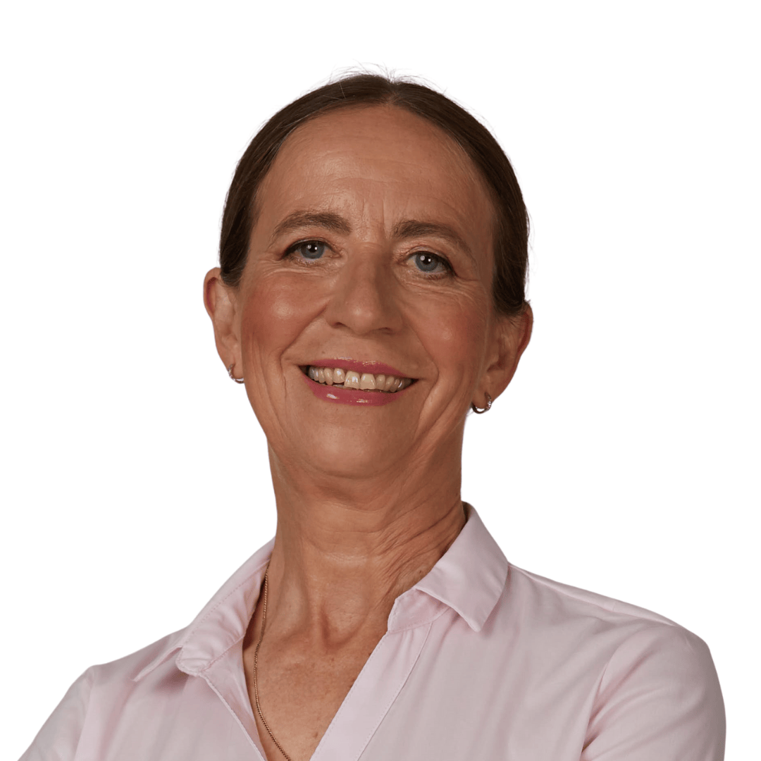 Žena s hnědými vlasy sepnutými dozadu, ve světle růžové košili s límečkem, se usmívá do kamery na obyčejném bílém pozadí.