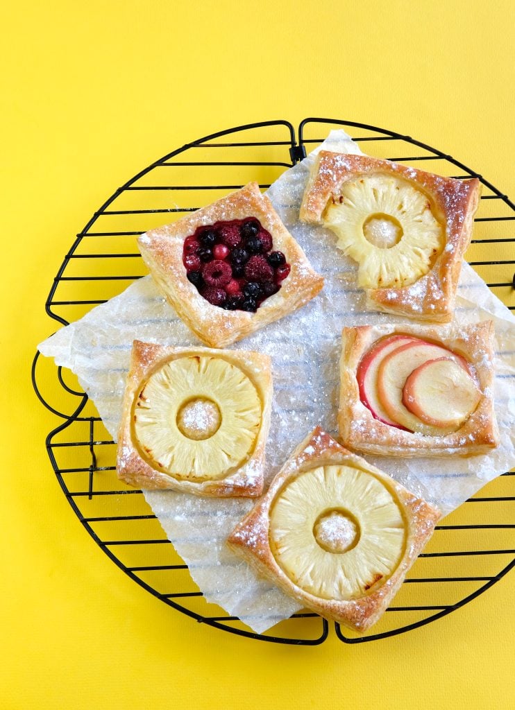 Golden puff pastry slices topped with pineapple rings and dusted with icing sugar.