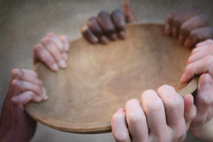 hands of various skin colors holding on to an empty bowl
