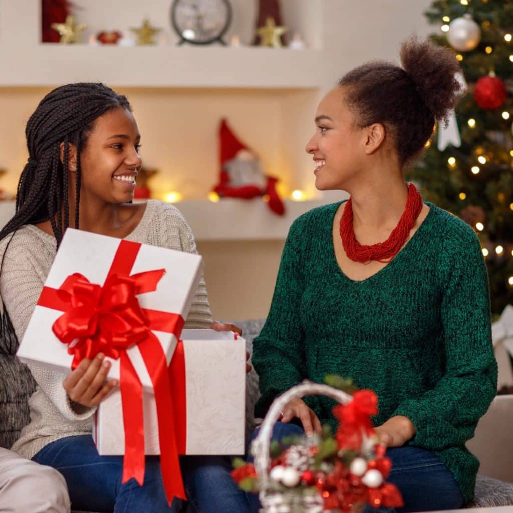 Two women sitting on a couch exchanging gifts
